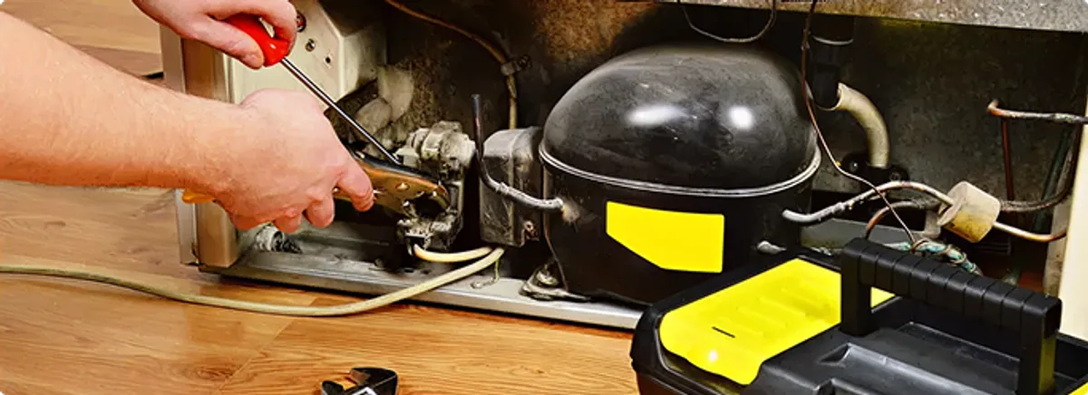 Refrigerator repair technician fixing the compressor and wiring in Bethany, LA